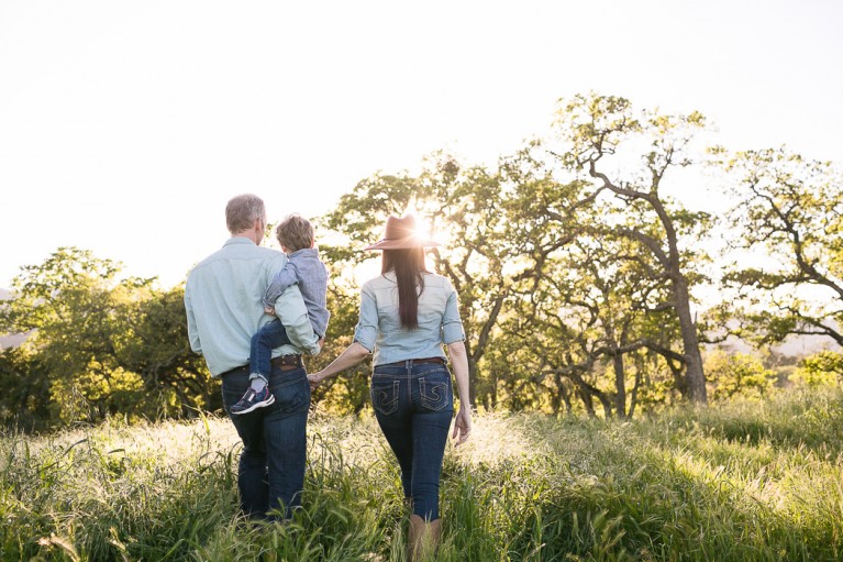 backlit photo of a family of 3 in a field by Kristin Dokoza