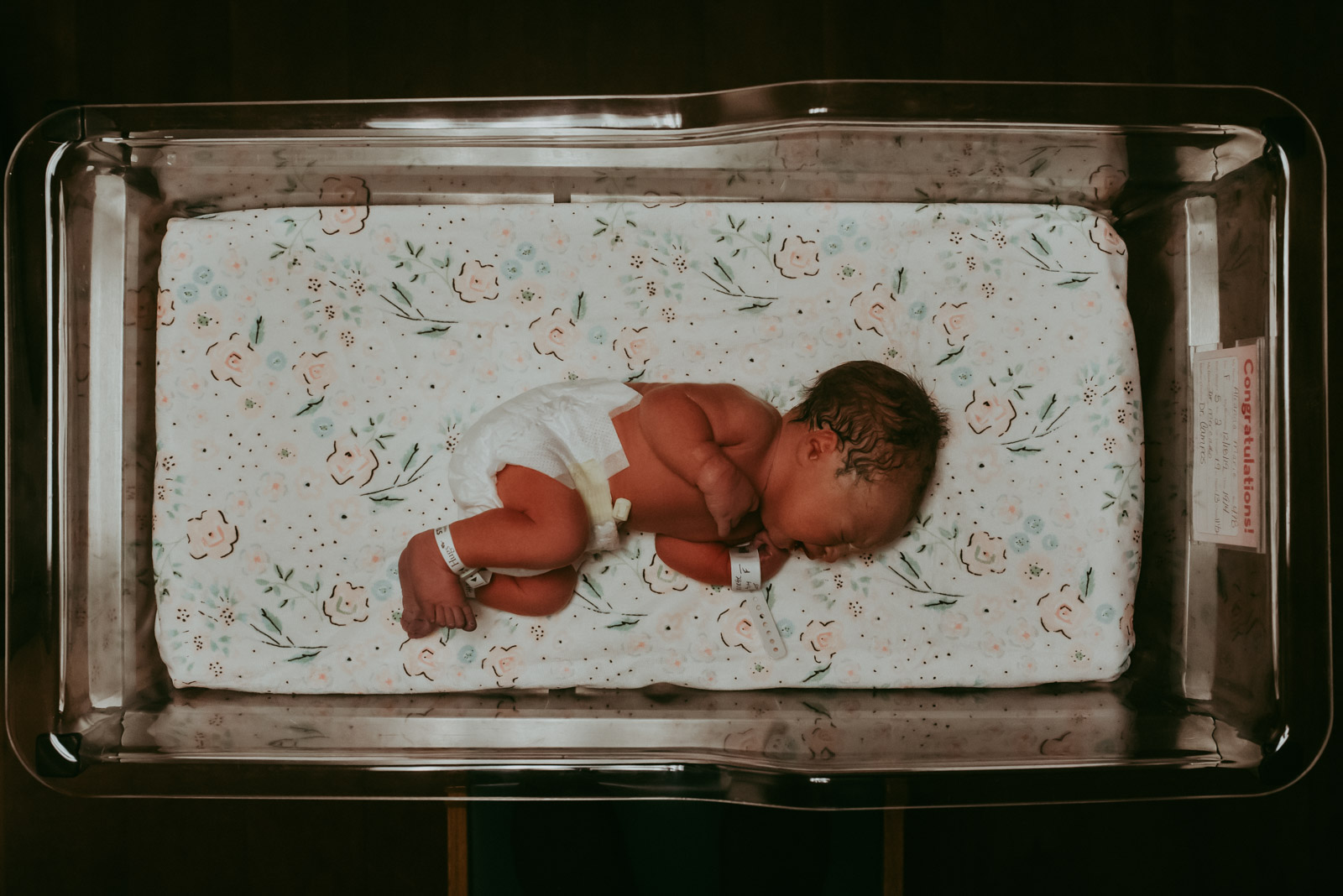 Birth-Photography-Jessica-Miles-09 Newborn baby in hospital crib with flowered sheets