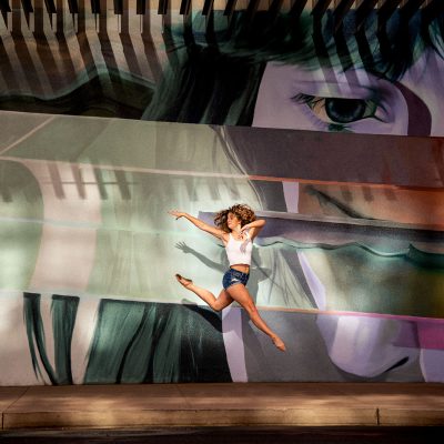 Dancer jumps against colorful wall during dance photo shoot outdoors