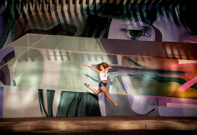 Dancer jumps against colorful wall during dance photo shoot outdoors