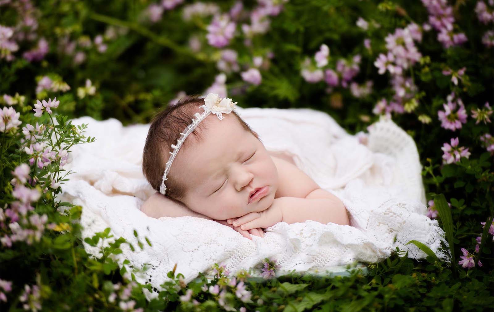 Adorable newborn baby girl surrounded by flowers