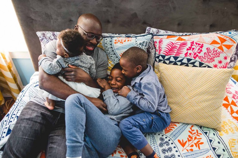 A dad snuggling his three children. Photo by Lucy Baber.