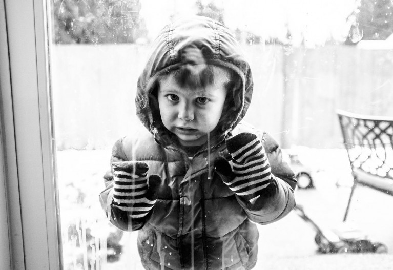finding inspiration in bad weather, a boy in winter gear looks in a window