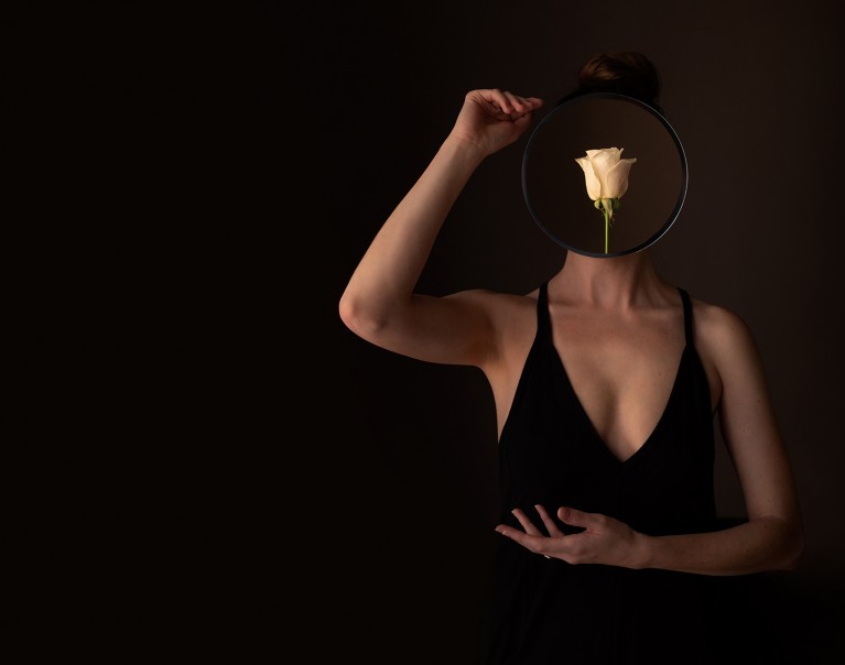 Creative selfie of woman with flower over her face