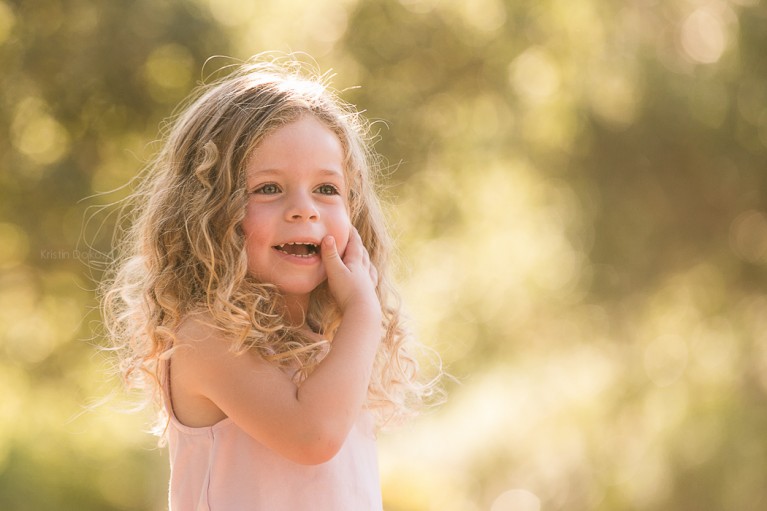girl with curly hair smiling by Kristin Dokoza