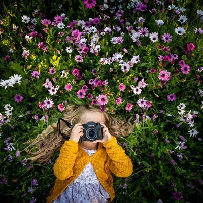 Girl with camera in flower field - How to buy a camera