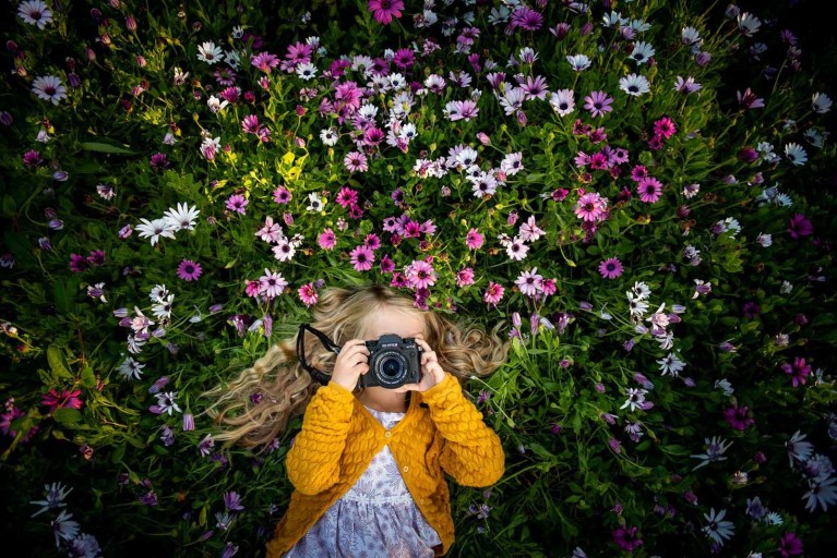 Girl with camera in flower field - How to buy a camera