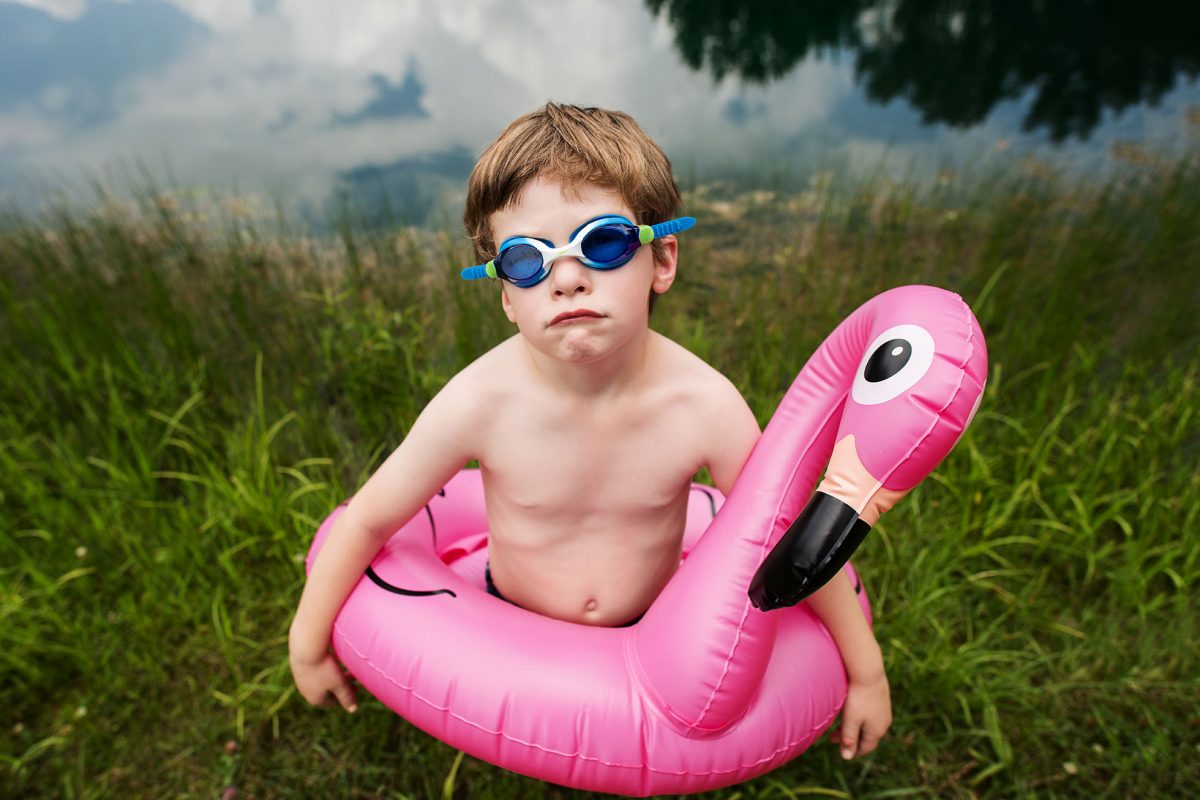 kellie-bieser-flamingo-floatie Boy with flamingo pool floatie and a pout