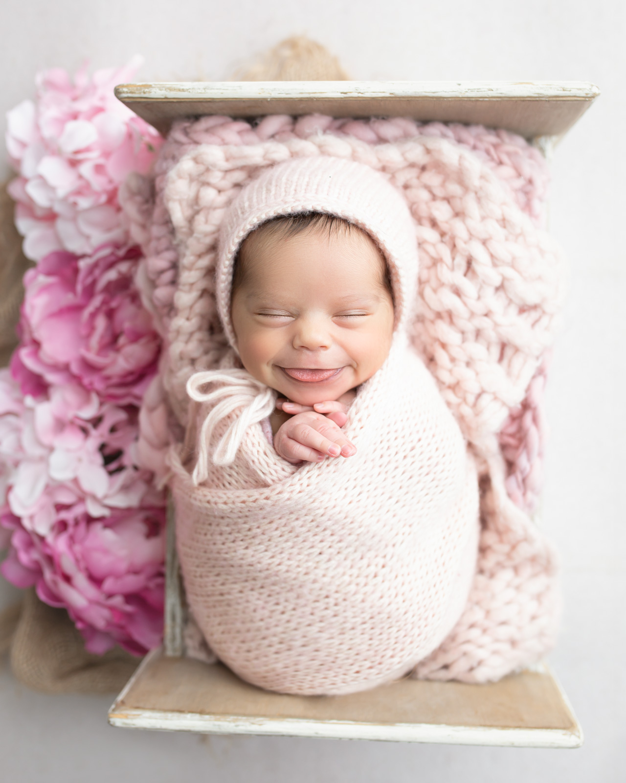 Stress-free newborn pose of newborn baby smiling