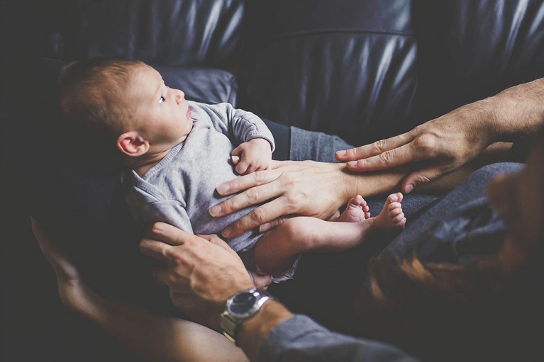 lifestyle picture of mom and dad holding newborn by Erin Schmidt