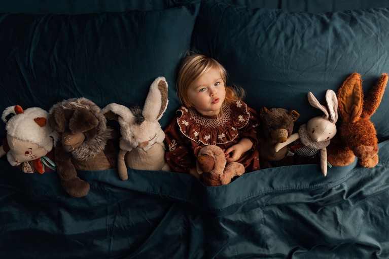 Little girl in bed with stuffed animals, taken with Profoto A10 light