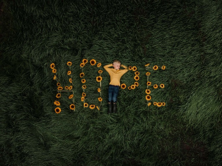 Boy laying on word Hope spelled in gold flowers