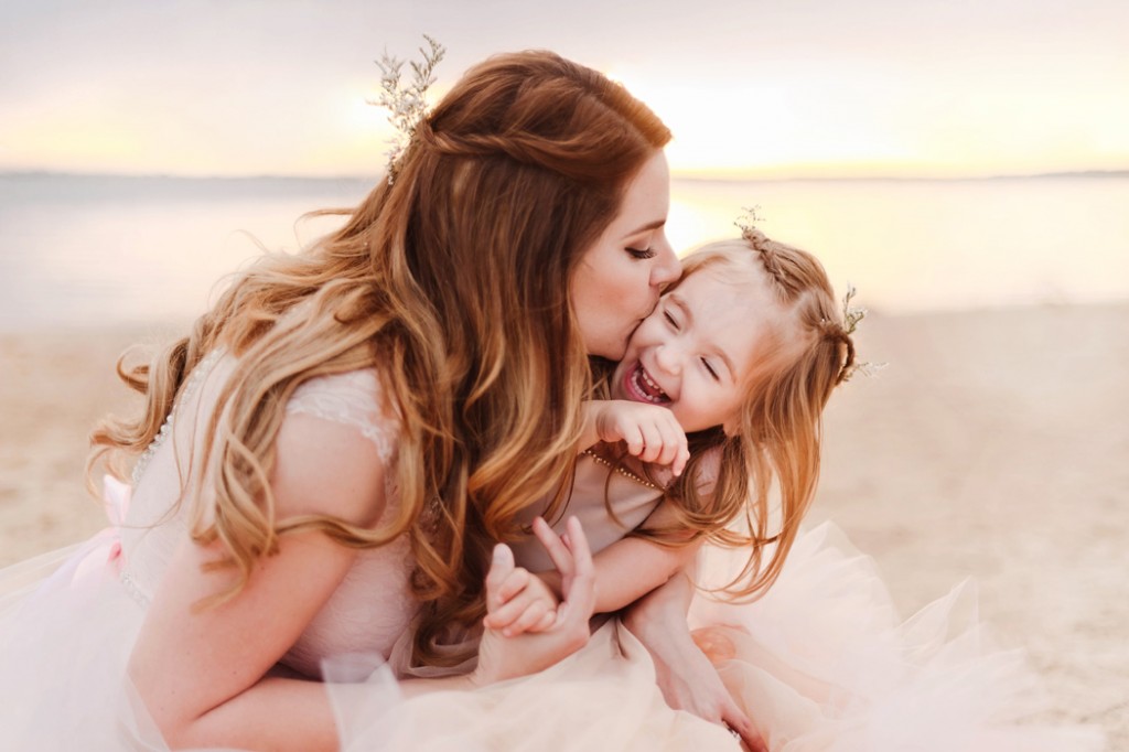 photo of mom giving daughter a kiss on the beach by Woodsy Wonders Photography