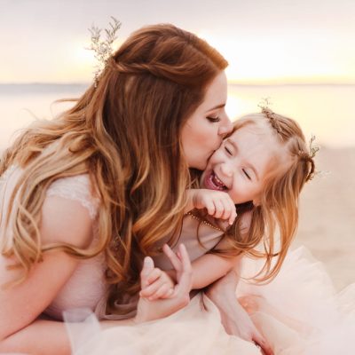 photo of mom giving daughter a kiss on the beach by Woodsy Wonders Photography