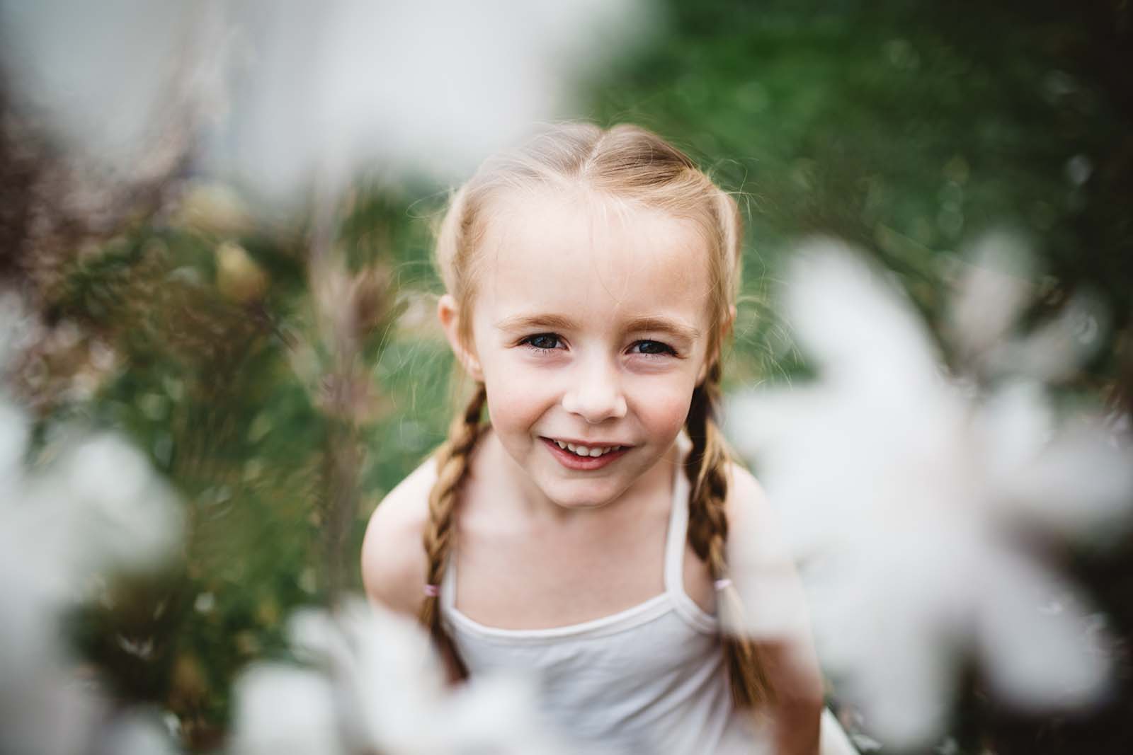 photographer-mom-laura-frazier-6 A smiling girl through flowers. Finding balance with photography and motherhood