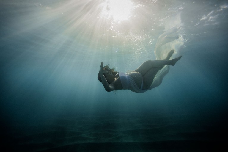 Pregnant woman in ocean during underwater maternity photo session