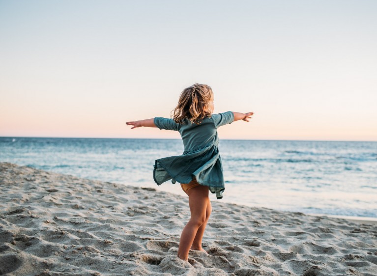 How to photograph special needs children - A girl twirls on the beach.