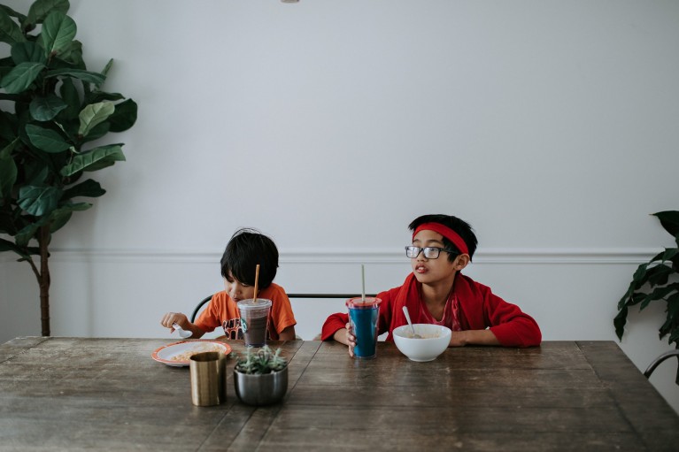 Two boys eat at a dining room table by Winnie Bruce