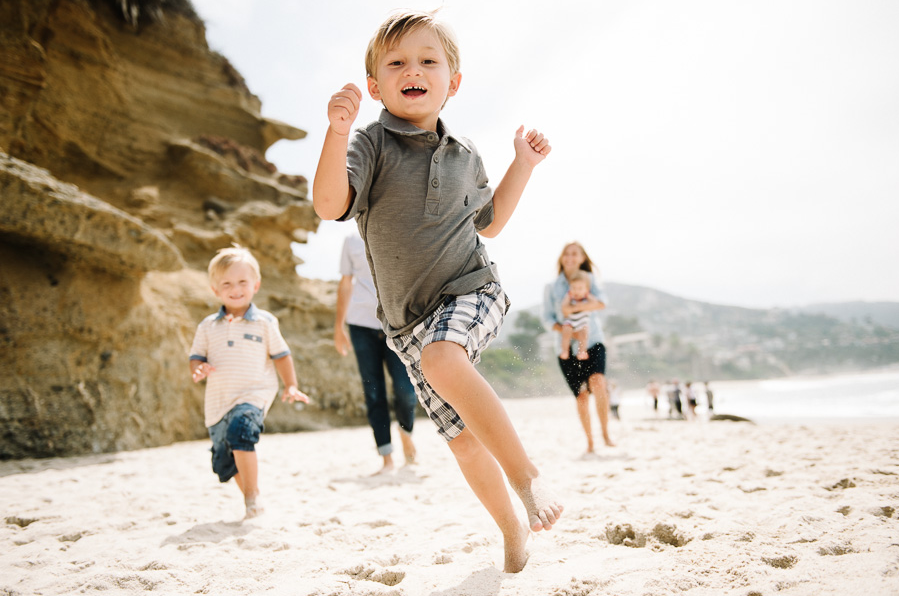 photo of boy skipping on the beach with his family by Jen J Photography