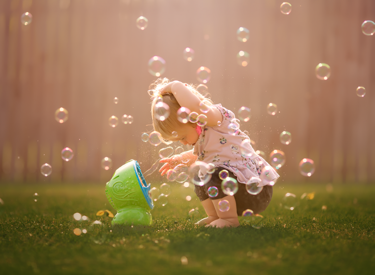 picture of girl playing in a bubble machine by Kate Luber